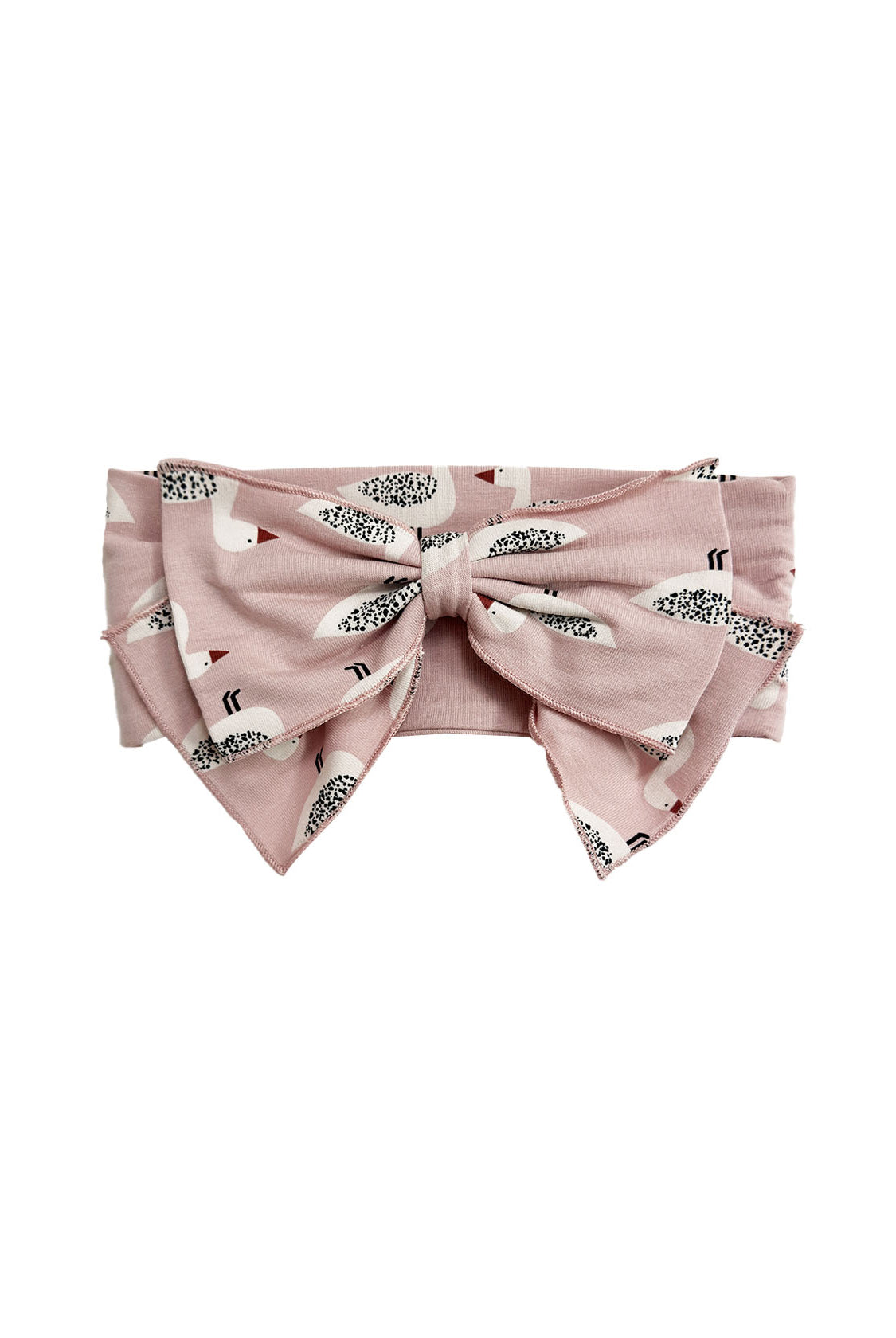The Ducky in Pink Hair Accessory by Mabel and Honey is a pink headband with an oversized bow, decorated with a playful pattern of small white birds featuring black and brown details.