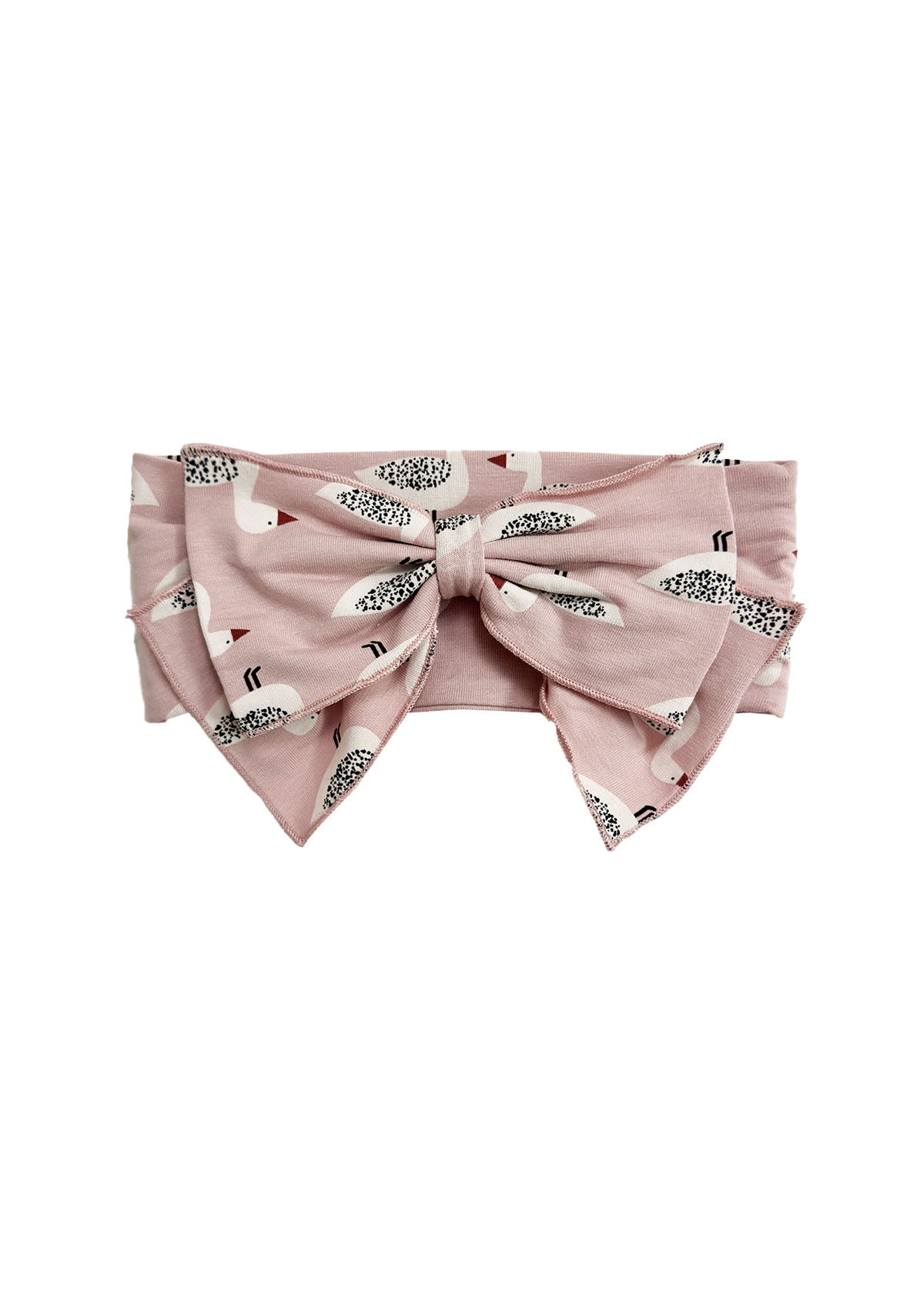The Ducky in Pink Hair Accessory by Mabel and Honey is a pink headband with an oversized bow, decorated with a playful pattern of small white birds featuring black and brown details.