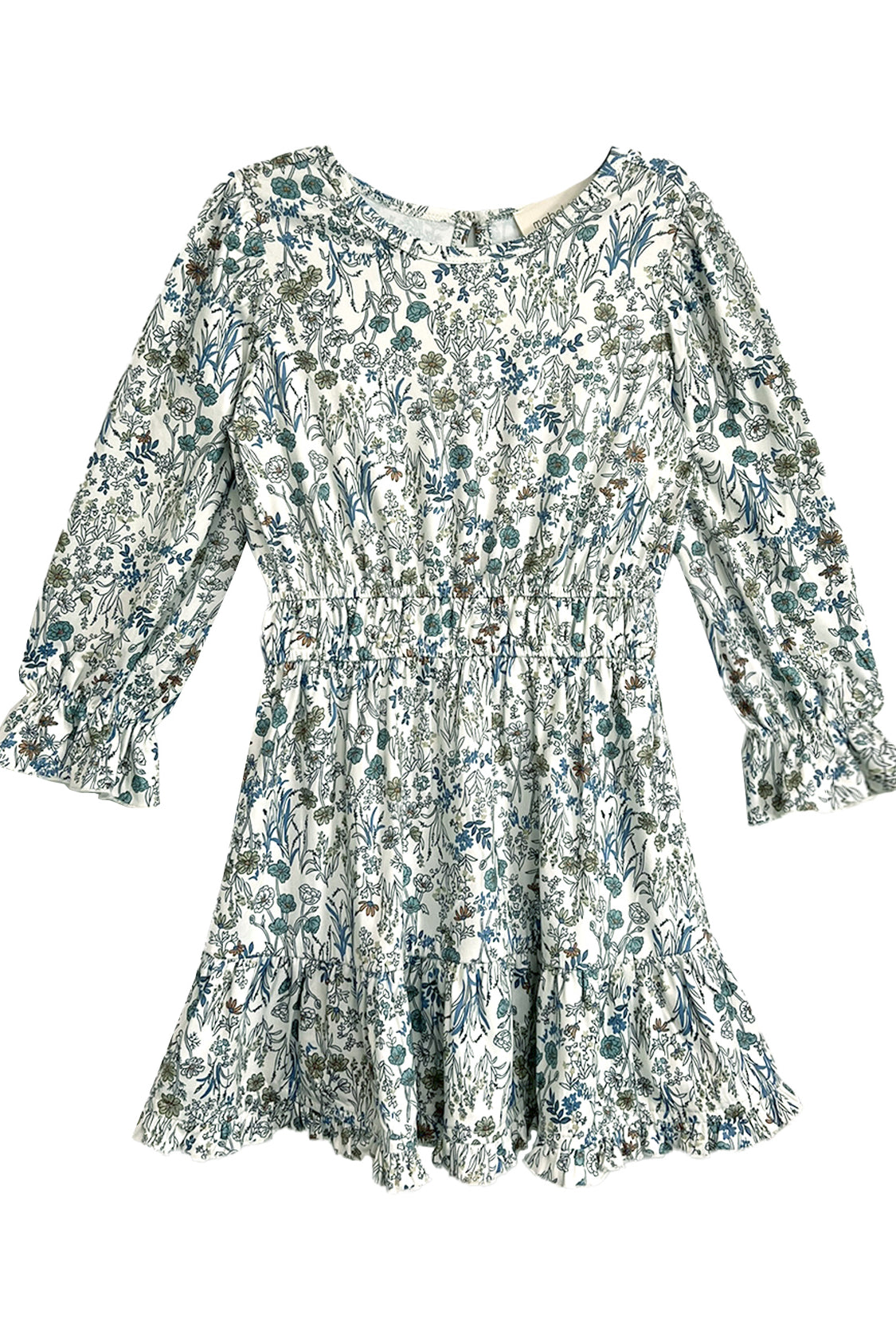 The Brooklyn Floral Dress by Mabel and Honey is a long-sleeve white dress with a green and blue floral pattern, cinched waist, ruffled cuffs, and ruffled hem.