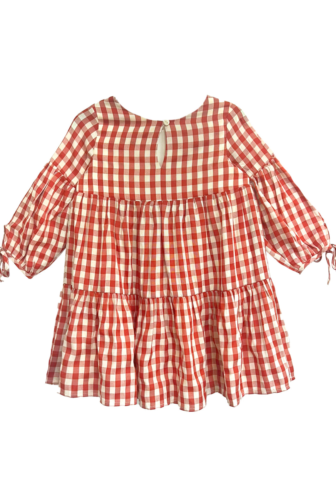 The Tis’ the Season Dress by Mabel and Honey is a loose-fitting girls’ holiday dress featuring red and white gingham, long sleeves with cuff ties, a tiered skirt, and a round neckline with back button keyhole.