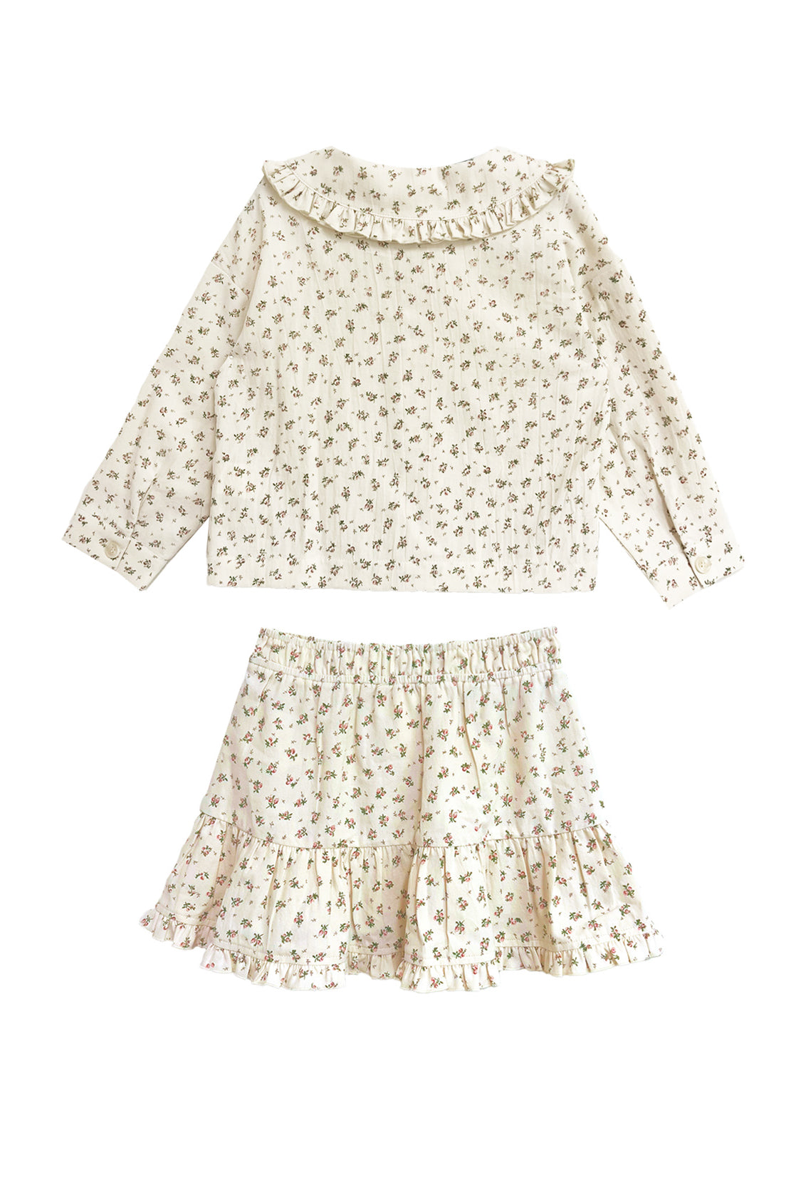 The Juliette Two Piece Set by Mabel and Honey is a charming girls’ outfit featuring an off-white long-sleeve top with ruffle collar and a matching floral ruffle skirt.
