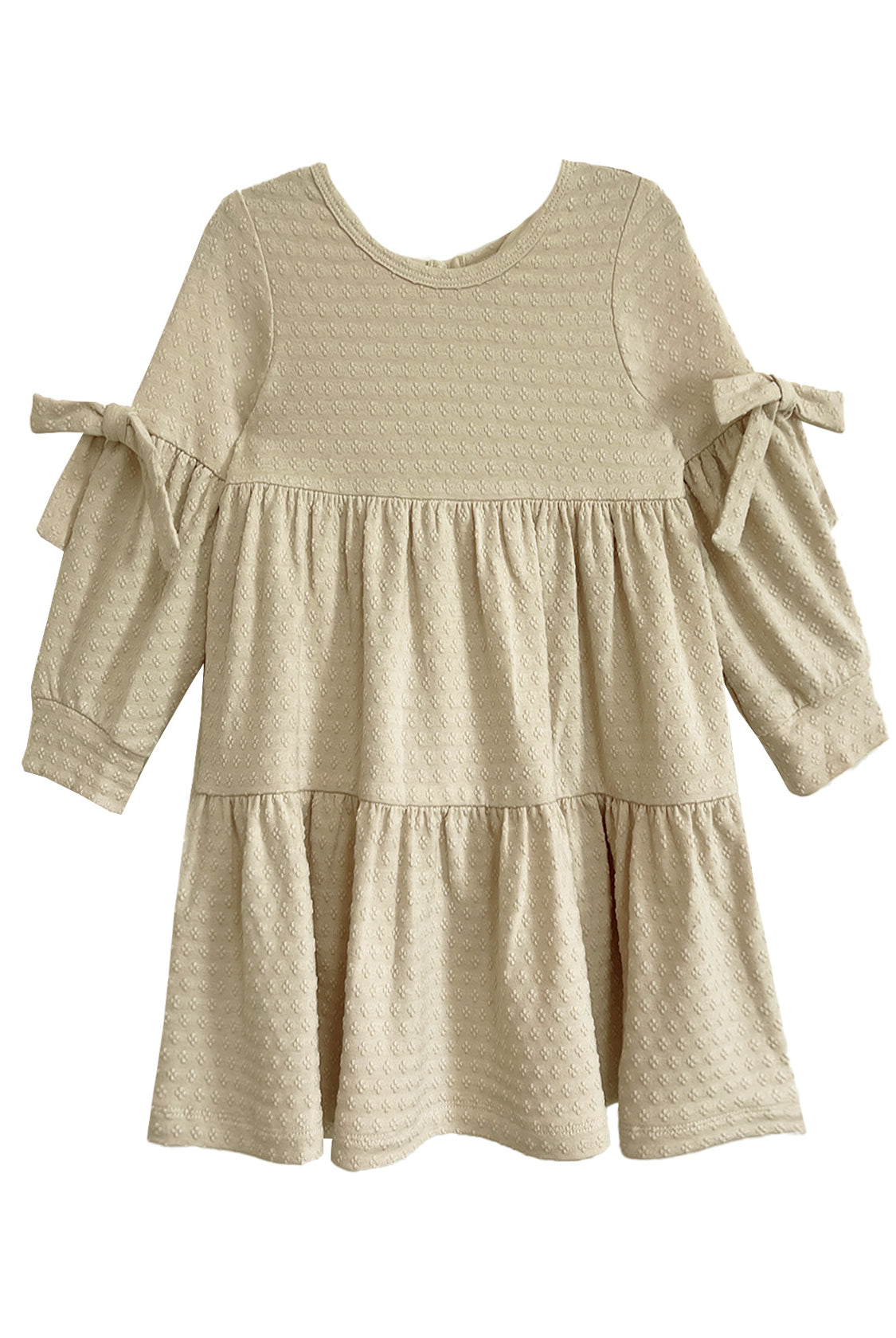 The Mabel and Honey Cinnamon Sugar Dress is a cream-colored toddler dress with textured fabric, a tiered silhouette, long sleeves, and decorative bows on each sleeve.
