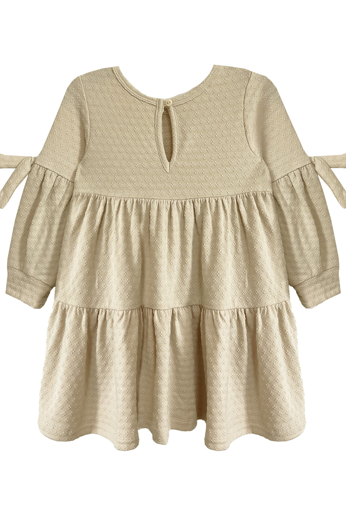 The Cinnamon Sugar Dress by Mabel and Honey features a cream, long-sleeve tiered design with textured dot fabric, ruffled skirt, small bow ties on the arms, and a keyhole button closure at the back for easy dressing.