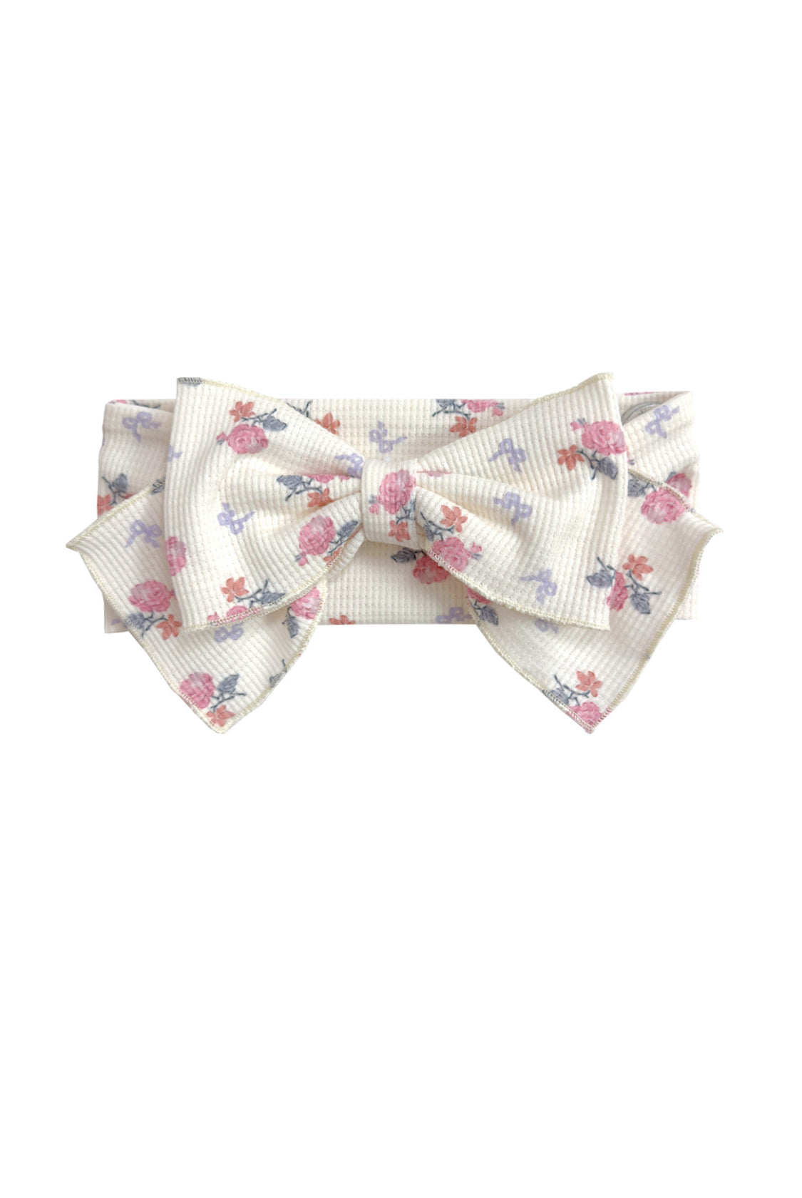 The Mia Hair Accessory by Mabel and Honey is an ivory ribbed fabric headband with a large bow, adorned with a pink and purple floral design.