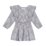 The Frost Rayon Dress by Mabel + Honey is a light purple, long-sleeve dress for little girls featuring a white wildflower print, ruffled shoulders, and a smocked waist. With its round neckline and flowy skirt, this dress is perfect for any special occasion.