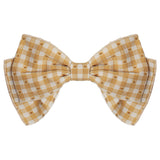 The Field of Flowers Headband by Mabel and Honey features a yellow and white checkered pattern with a layered double-bow design, made from 100% cotton and shown on a plain white background.