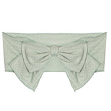 The Meadow Breeze Headband by Mabel and Honey is a light green, wide cotton fabric headband with a subtle polka dot pattern and a large bow at the center—perfect as a sweet baby hair accessory.