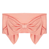 The Addison Pink Headband by Mabel and Honey is a wide, soft cotton baby accessory with a large, petal-like bow at the front center. The stretchy fabric ensures comfort and style for your little one.
