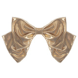 The Shine Bright Headband by Mabel and Honey features a metallic gold bow with wide loops and tails, making it a perfect baby hair accessory, displayed against a white background.