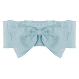 The Butterfly Kisses Blue Headband by Mabel and Honey is a light blue cotton accessory featuring a large decorative bow, subtle texture, and ruched details at the back—perfect for adding stylish charm to any baby's outfit.