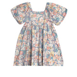 The Flower Mae Floral Dress by Mabel and Honey is a knee-length girl's dress with puff sleeves, a square neckline, and a vintage-inspired floral print on a light background—perfect for young girls.
