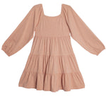 The Flower Mae Pink Dress by Mabel and Honey is a light pink, long sleeve tiered dress with a square neckline, gathered waist, elastic cuffs, bow back detail, and a loose flowy fit crafted from soft lightweight fabric.