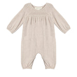 The Millie Romper by Mabel and Honey is a light beige long-sleeve one-piece with gathered elastic cuffs, a smocked pleated chest, and a classic round neckline.