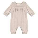 The Millie Romper by Mabel and Honey is a light beige long-sleeve one-piece with gathered elastic cuffs, a smocked pleated chest, and a classic round neckline.