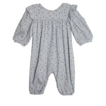 The Twinkle Twinkle Romper by Mabel and Honey features a blue-gray design with long puffed sleeves, elastic cuffs, ruffled shoulders, and a soft, lightweight fabric adorned with small black dots.