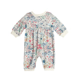 The Melody Romper by Mabel and Honey is a pastel long sleeve romper with pink, blue, and beige florals on white. It features comfy white cuffs at the sleeves, ankles, and neckline for a cozy finish.