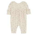 The Mabel and Honey Breakfast in Bed Romper is a cream-colored baby girls’ piece with a green floral print, ruffled sleeves, and gathered fabric for a soft, vintage-inspired look.