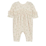 The Mabel and Honey “Breakfast in Bed Romper” is a cream-colored long-sleeve baby girls romper with ruffled sleeves, chest and cuff accents, and a delicate green floral pattern. Displayed flat on a white background.