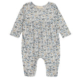 The Mabel and Honey Hazelnut Romper is a long-sleeved baby girl romper with a gathered waist and a blue, beige, and gray floral print, shown flat on a white background.