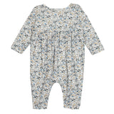 The Hazelnut Romper by Mabel and Honey is a long sleeve baby girl outfit with blue, beige, and green florals on white, gathered chest fabric, and closed feet.