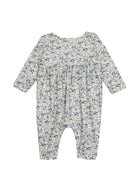 The Hazelnut Romper by Mabel and Honey is a long sleeve baby girl outfit with blue, beige, and green florals on white, gathered chest fabric, and closed feet.