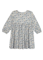 The Hazelnut Dress by Mabel and Honey is a loose-fitting, long sleeve girl’s dress with a high waist, blue-green-beige floral print, round neckline, flowy silhouette, and is ideal for casual special occasions.