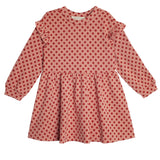 The Red Velvet Dress by Mabel and Honey features long sleeves, ruffled shoulders, a gathered skirt, and playful red polka dots for a charming, feminine look.