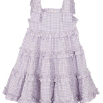 The Super Bloom Tiered Dress by Mabel and Honey is a sleeveless, knee-length lavender gingham dress with white checks, ruffled tiers, and wide shoulder straps tied in bows.