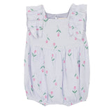 The Mabel and Honey Tiny Tulip Baby Romper features soft, lightweight lavender gauze, ruffled shoulder straps, and a charming pattern of pink tulips with green stems.