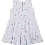 The Tiny Tulip Drop Waist Dress by Mabel and Honey is a sleeveless white girl's dress with a flared, tiered skirt, pink tulip print with green stems, and a teardrop button closure at the back neckline for easy dressing.