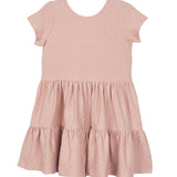 The Mabel and Honey Josie Dress is a blush pink short-sleeve girl's dress with a round neckline, tiered ruffled skirt, and subtle textured fabric, shown laid flat on a white background.