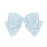 The Ella Hair Accessory by Mabel and Honey features a large, light blue fabric bow with layered, pointed ends—a charming girl's accessory displayed on a plain white background.