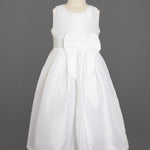 The Taffeta Bow Communion Dress w/ Beaded Pearl Neckline by Mabel and Honey is a sleeveless white girls’ dress with a full skirt, pearl-trimmed neckline, and large waist bow, shown on a dress form against a plain gray background.