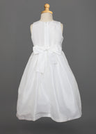 The Mabel and Honey Taffeta Bow Communion Dress features a sleeveless white design, full taffeta skirt, large back bow, and a beaded pearl neckline, displayed on a dress form against a gray background.