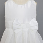The Mabel and Honey Taffeta Bow Communion Dress features a beaded pearl neckline and a large decorative waist bow, displayed on a mannequin against a plain gray background.