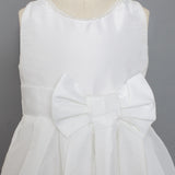 The Mabel and Honey Taffeta Bow Communion Dress features a beaded pearl neckline and a large decorative waist bow, displayed on a mannequin against a plain gray background.