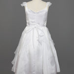 The Mabel and Honey Chiffon Ruffle and Satin Flower Girl Dress, shown on a mannequin with ruffled skirt layers, hand-beaded embellishment, and tied waist belt, is displayed against a plain gray background.