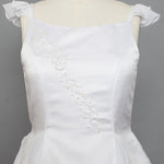 The Mabel and Honey Chiffon Ruffle and Satin Flower Girl Dress features ruffle cap sleeves and hand beaded embellishments, displayed on a mannequin against a gray background.