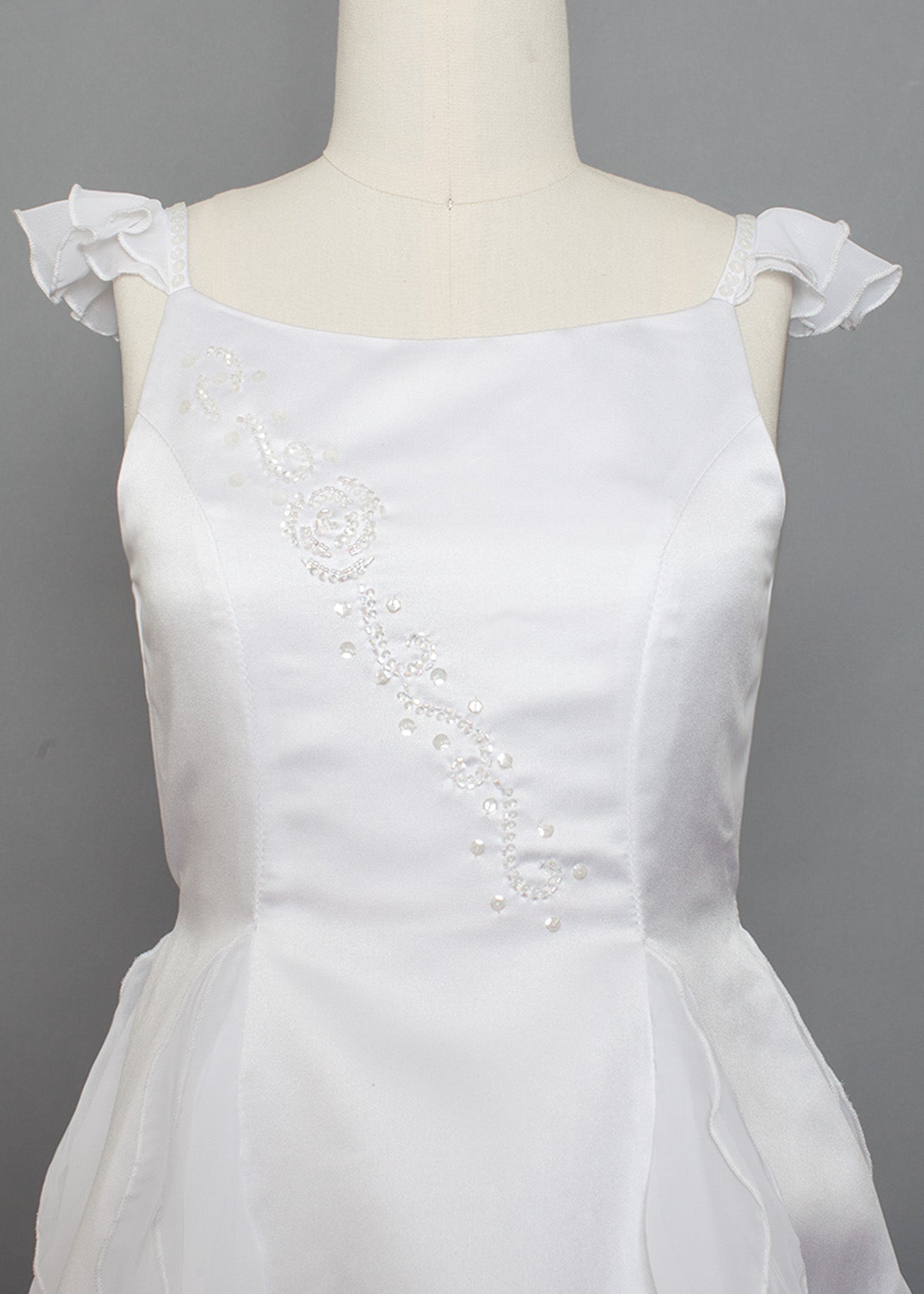 The Mabel and Honey Chiffon Ruffle and Satin Flower Girl Dress features ruffle cap sleeves and hand beaded embellishments, displayed on a mannequin against a gray background.