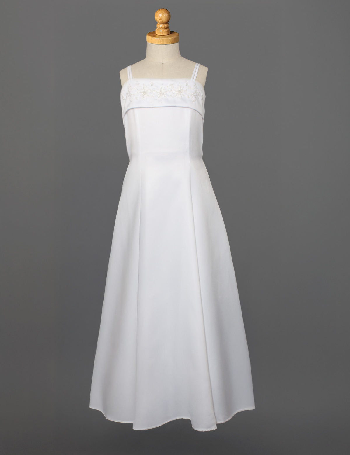 The Mabel and Honey Satin A-Line Communion Dress features hand beaded embellishments, a sleeveless design, and thin straps, shown on a mannequin against a plain gray background.