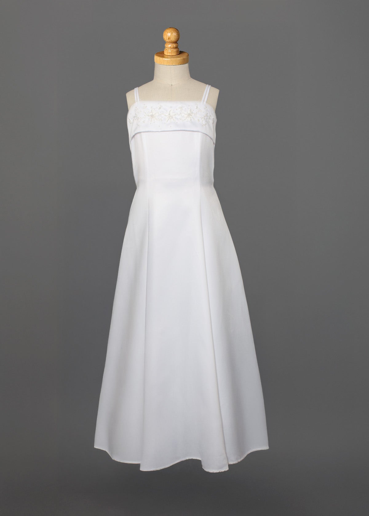 The Mabel and Honey Satin A-Line Communion Dress features hand beaded embellishments, a sleeveless design, and thin straps, shown on a mannequin against a plain gray background.