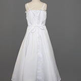 The Mabel and Honey Satin A-Line Communion Dress features hand-beaded embellishments, a sleeveless white design with thin straps, two bows at the chest and waist, displayed ankle-length on a dress form against a gray background.