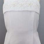 The Mabel and Honey Satin A-Line Communion Dress features a sleeveless design with thin straps, a straight neckline, and hand-beaded embellishments for an elegant, delicate look.