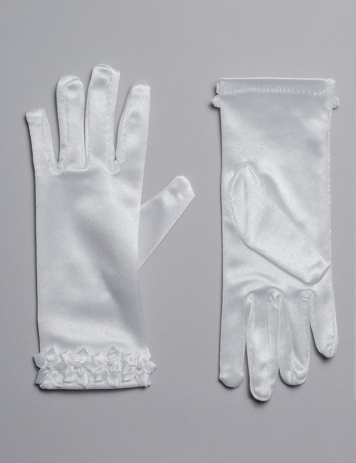 Lauren Marie Satin Flower Cuff Communion Gloves for girls, shown in white satin on a gray surface. One palm-up, one palm-down, each with delicate flower appliqué at the wrist—an elegant formal accessory.
