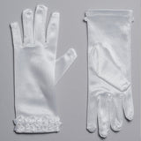 Lauren Marie Satin Flower Cuff Communion Gloves for girls, shown in white satin on a gray surface. One palm-up, one palm-down, each with delicate flower appliqué at the wrist—an elegant formal accessory.
