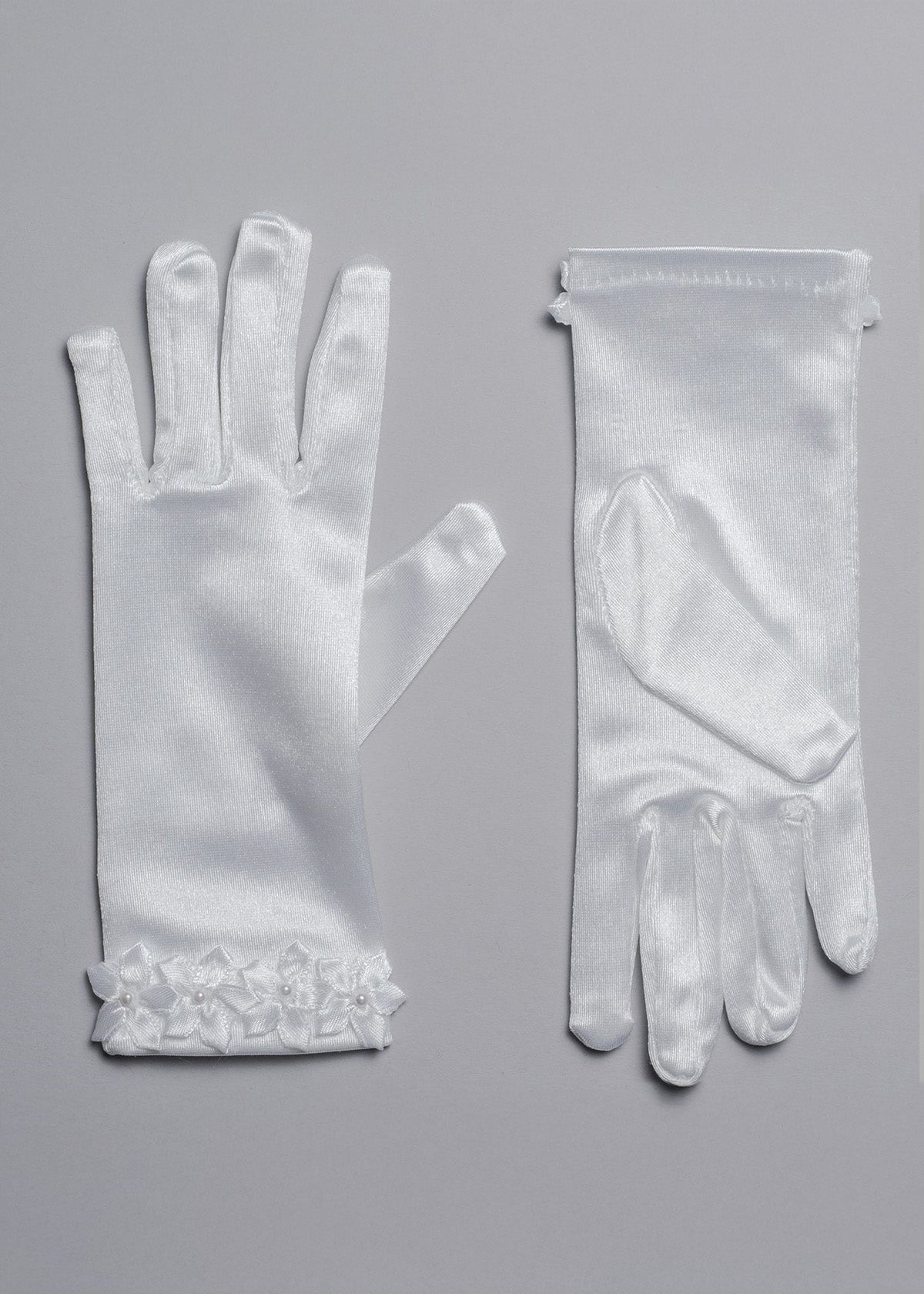 Lauren Marie Satin Flower Cuff Communion Gloves for girls, shown in white satin on a gray surface. One palm-up, one palm-down, each with delicate flower appliqué at the wrist—an elegant formal accessory.