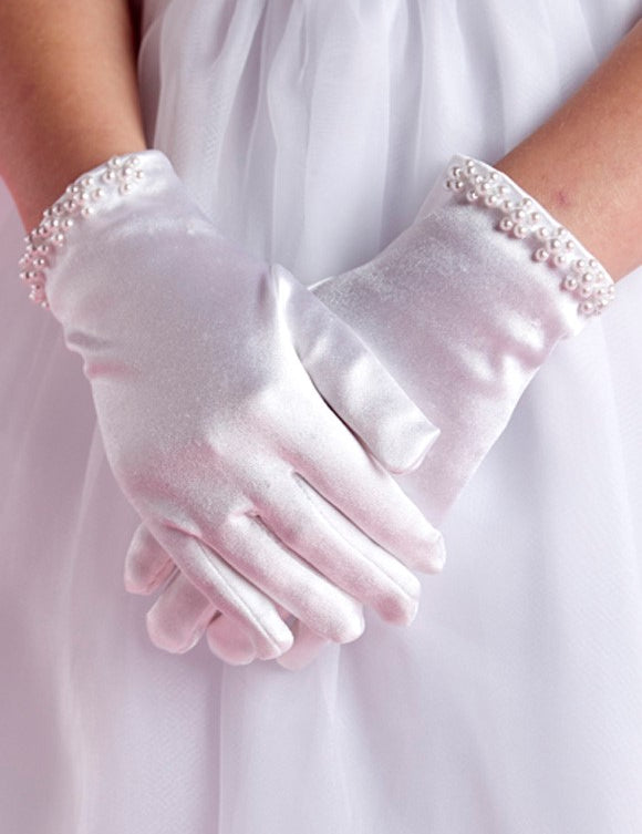 A person wearing Lauren Marie’s Pearl Cuff Gloves—white gloves adorned with elegant pearl beads and shiny cuffs—stands with hands gently clasped.