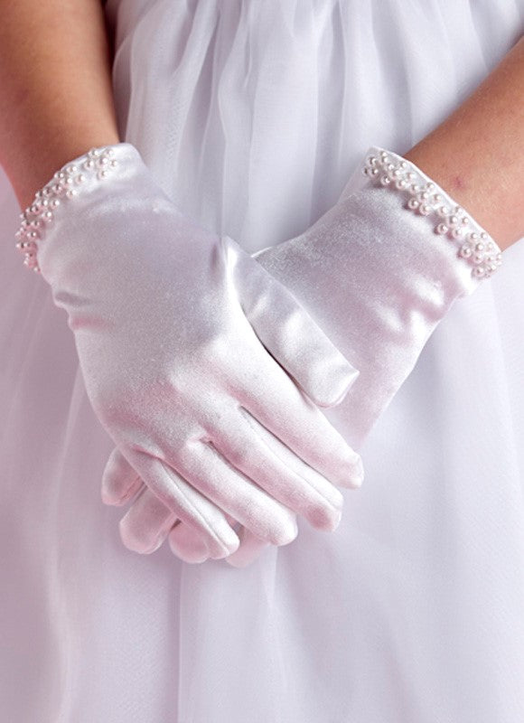 A person wearing Lauren Marie’s Pearl Cuff Gloves—white gloves adorned with elegant pearl beads and shiny cuffs—stands with hands gently clasped.