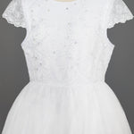 The Mabel + Honey Scalloped Detail on Waist and Sleeve Dress is a white First Communion dress with a lace bodice, delicate embroidery and sequins, cap sleeves, and a full organza tulle skirt. Shown on a mannequin against a gray background.