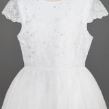 The Mabel + Honey Scalloped Detail on Waist and Sleeve Dress is a white First Communion dress with a lace bodice, delicate embroidery and sequins, cap sleeves, and a full organza tulle skirt. Shown on a mannequin against a gray background.